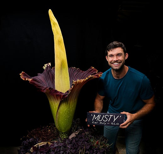Gage Willey, curator of the Cal Poly Plant Conservatory, poses with the blooming corpse flower.